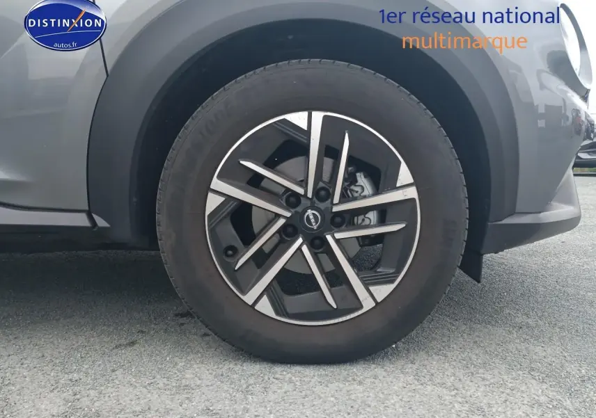 Gros plan sur la roue avant droite du Nissan Juke gris 2025 avec jante alliage et partie du pare-chocs avant visible.
