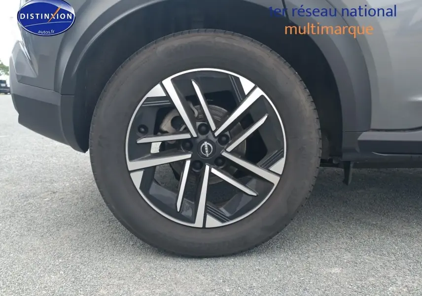 Gros plan sur la roue avant droite avec jante alu noire et argentée du Nissan Juke gris 2025.