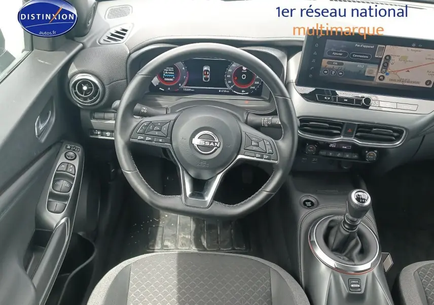 Vue intérieure centrée sur le volant cuir multifonction et levier de vitesse manuel du Nissan Juke gris 2025.