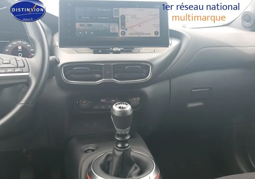 Intérieur de Nissan Juke gris 2025, vue centrée sur levier de vitesse manuel et écran tactile multifonction.