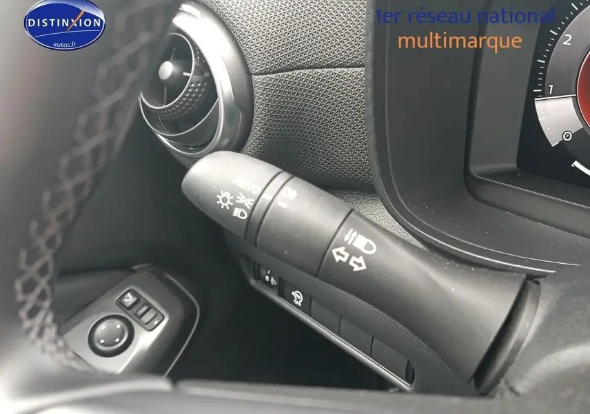 Gros plan sur la commande des clignotants et phares du tableau de bord noir du Nissan Juke gris 2025.