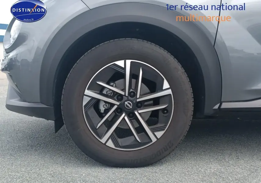 Gros plan sur la roue avant gauche du Nissan Juke gris 2025 avec jante alliage noire et argent.