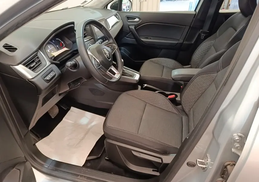 Vue intérieure côté conducteur du Renault Captur gris clair 2022, volant multifonctions en cuir synthétique et sièges tissu gris.