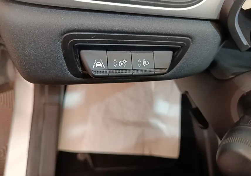 Gros plan sur les boutons de réglage de l'aide au maintien de voie et des phares dans l'habitacle du Renault Captur gris clair.