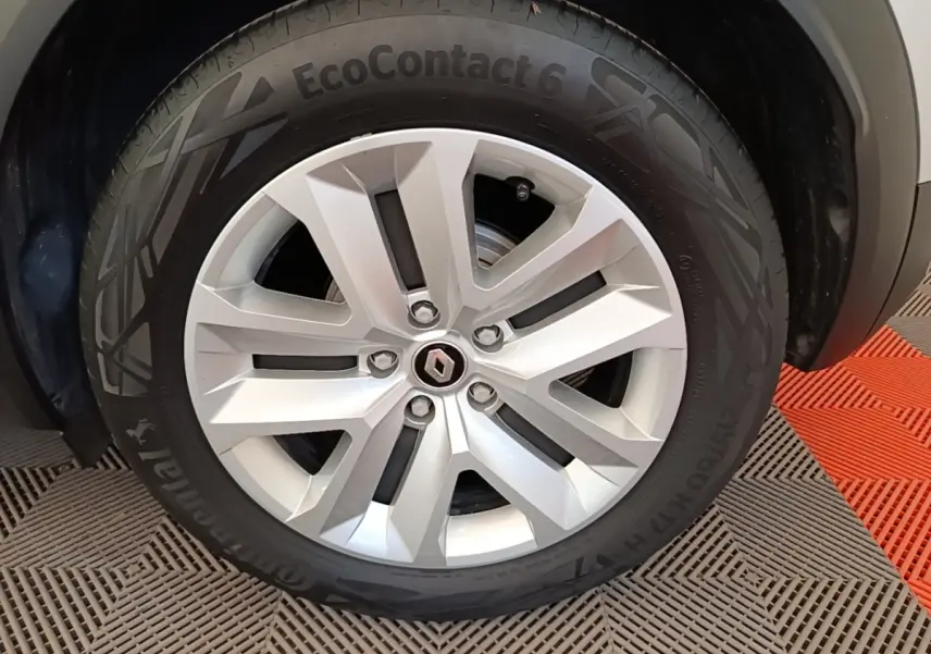Gros plan sur la jante alliage argentée avec logo Renault au centre du Renault Captur gris clair.
