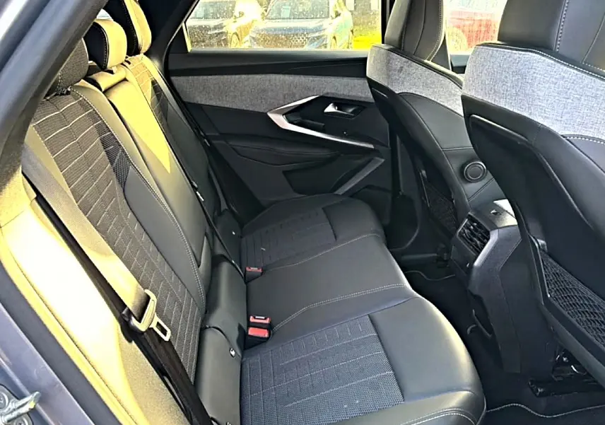 Vue intérieure arrière côté gauche du Peugeot 3008 gris 2025, sièges en tissu et cuir avec surpiqûres claires.