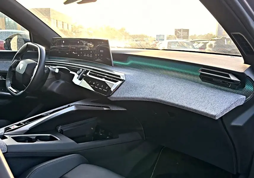 Vue intérieure côté passager du tableau de bord gris et noir du Peugeot 3008 1.2 hybrid 145 GT e-DCS6 avec écran tactile panoramique.