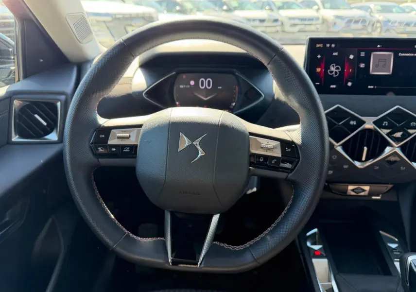 Vue intérieure centrée sur le volant du DS3 100 BVM6 Performance Line 2024, avec tableau de bord et écran tactile visibles.