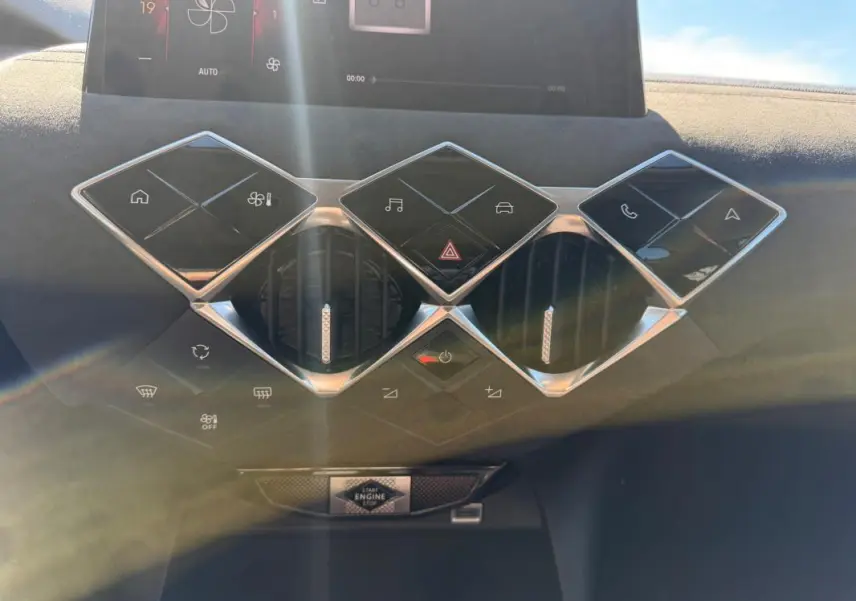Vue rapprochée de la console centrale du DS3 2024 gris, avec commandes tactiles en losange et aérateurs ronds chromés.
