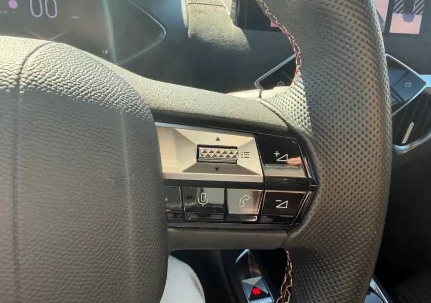 Détail du volant perforé avec commandes multifonctions du DS3 100 BVM6 Performance Line 2024 gris, vue rapprochée intérieure.