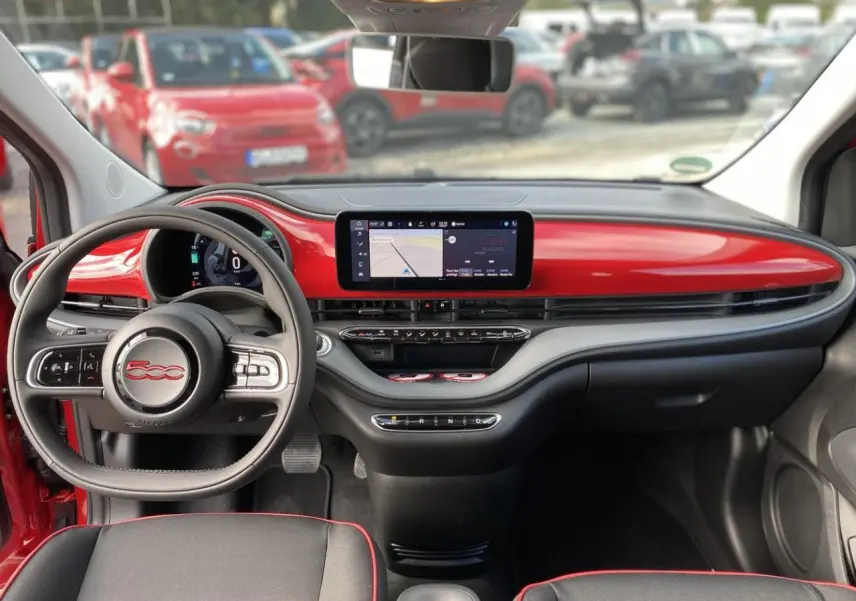 Intérieur de la Fiat 500 Cabriolet Electrique rouge, vue frontale sur le tableau de bord et volant avec écran tactile.
