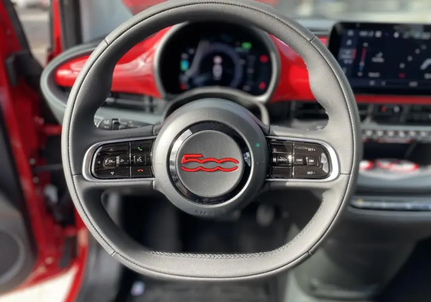 Volant noir avec logo rouge 500 au centre, tableau de bord numérique et intérieur rouge vif d'une Fiat 500 Cabriolet Electrique 2022.