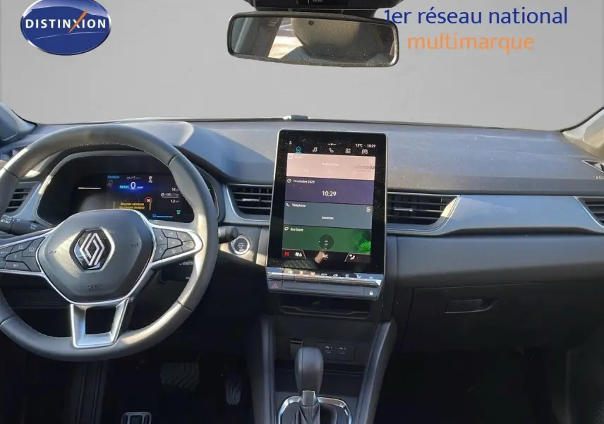 Intérieur du Renault Captur E-Tech hybride 2025 montrant le tableau de bord avec écran tactile vertical et volant multifonction.