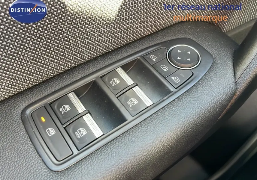 Gros plan sur les commandes des vitres électriques et rétroviseurs du côté gauche d'un Renault Captur gris Rafale métal toit noir.