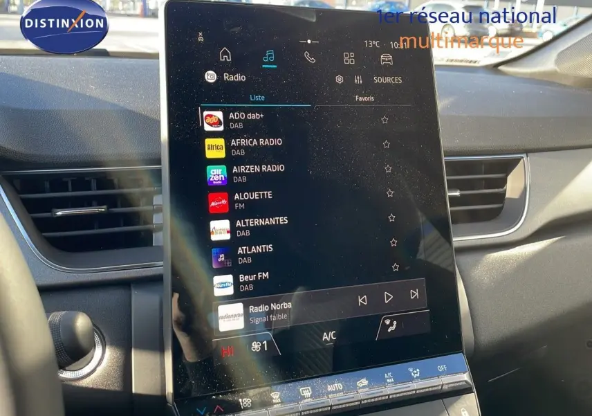 Écran tactile central allumé avec menu radio, intérieur gris du Renault Captur E-Tech hybride 2025 visible de face.