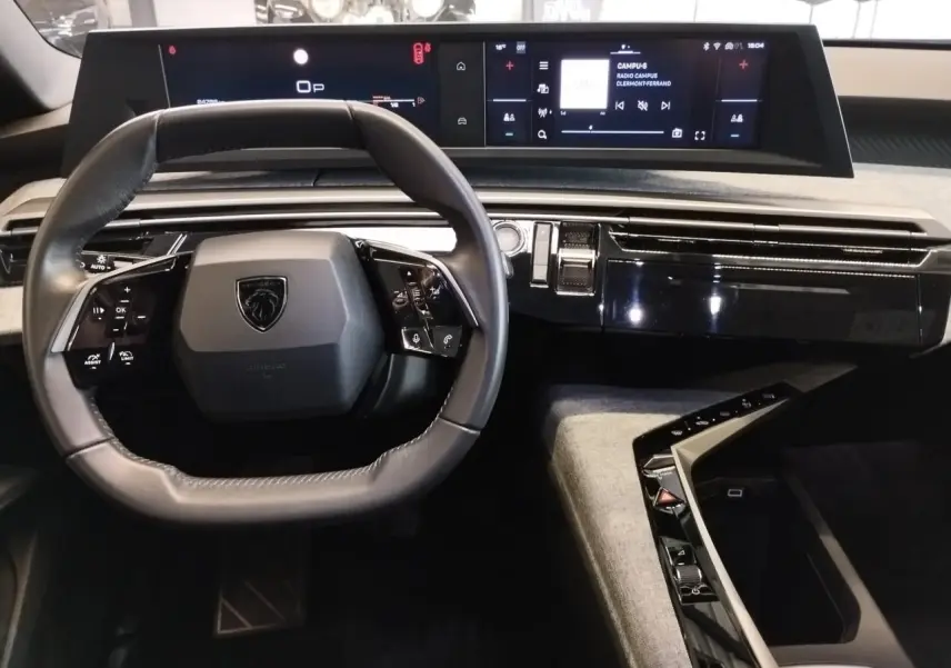 Vue intérieure centrée sur le volant compact et le tableau de bord numérique du Peugeot 5008 gris titanium 2025.