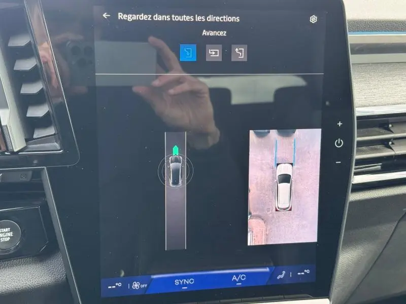 Vue rapprochée de l’écran central du Renault Austral 2025 montrant l’aide au stationnement avec vue aérienne du véhicule.