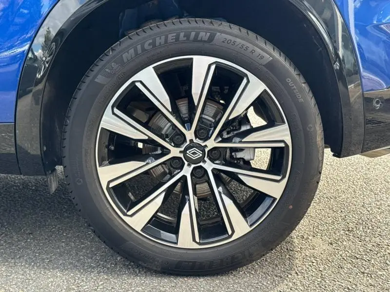 Gros plan sur la roue avant droite du Renault Austral 2025 bleu Outremer avec jante alliage noire et argentée.