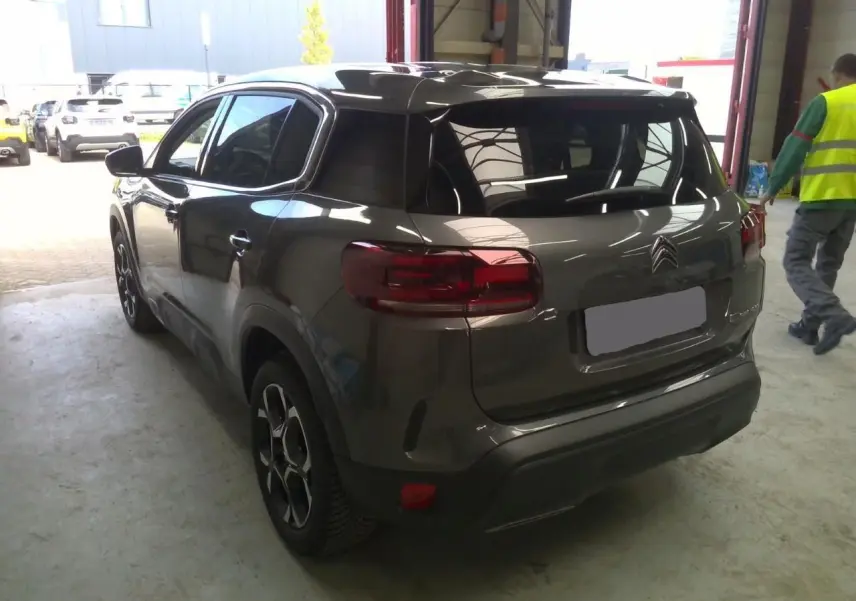 Vue 3/4 arrière du Citroën C5 Aircross gris platinium 2025, soulignant ses feux arrière et jantes distinctives.