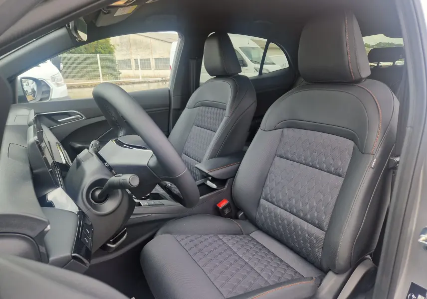 Vue intérieure côté conducteur du MG3 1.5L HYBRID+ 195CH Luxury avec sièges noirs en tissu et cuir, volant multifonction.