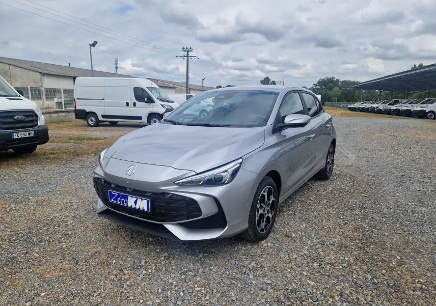 MG3 1.5L Hybrid+ 195ch Luxury en Cosmic Silver Metal, vue 3/4 avant droit sur parking gravillonné.