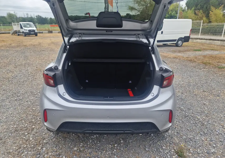 Vue arrière du coffre ouvert de la MG3 1.5L Hybrid+ 195ch Luxury en Cosmic Silver Metal sur sol gravillonné.