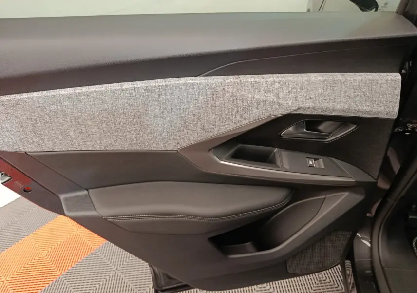 Vue intérieure côté gauche de la porte avant noire du Peugeot 3008 1.2 Hybrid avec insert tissu gris clair.