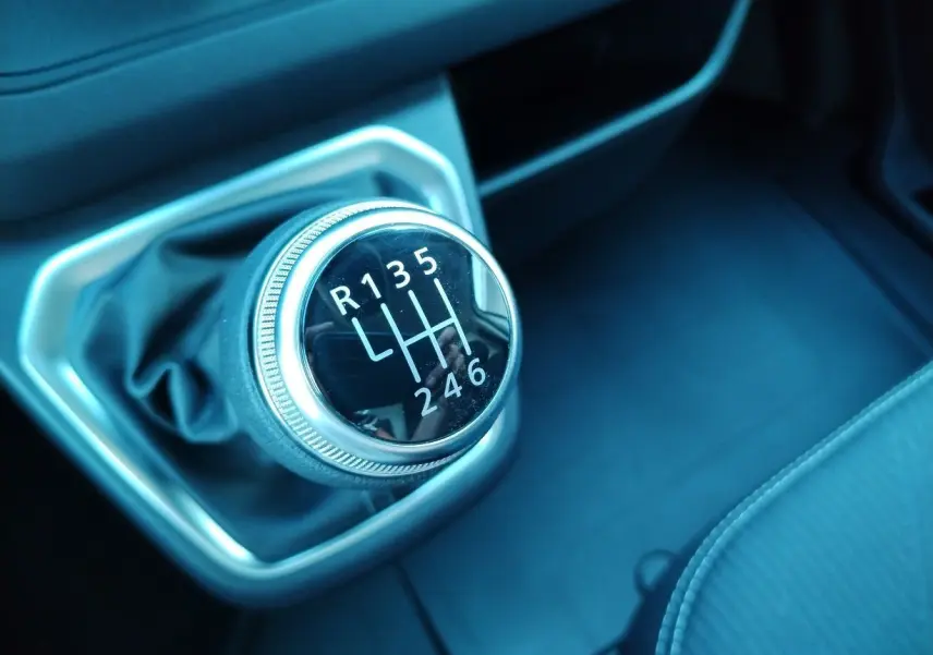 Gros plan sur le levier de vitesse manuel noir et chrome du Nissan Primastar 2025 à intérieur sombre.