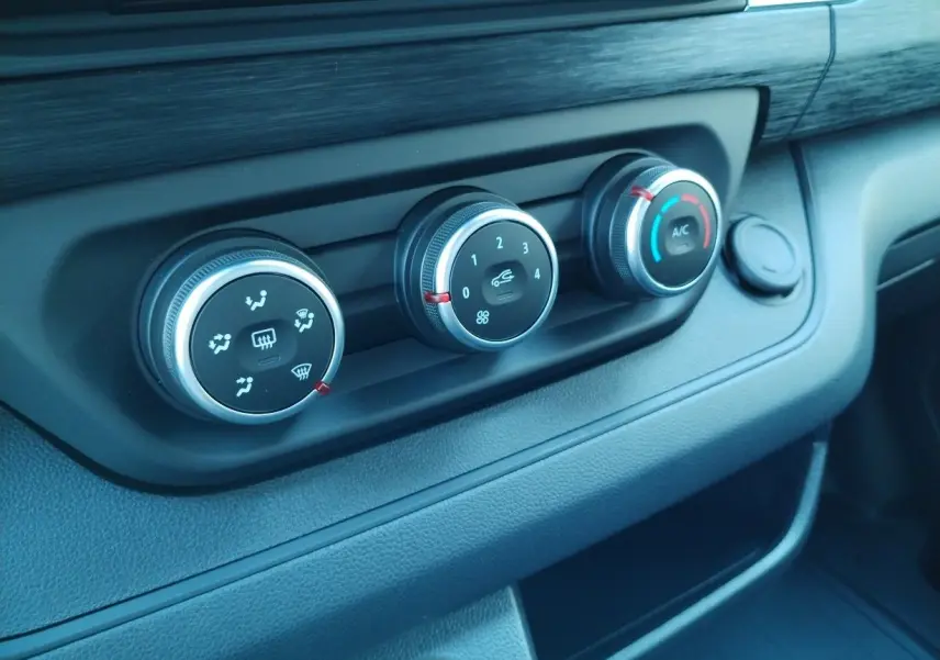 Gros plan sur les commandes de climatisation noires et argent du tableau de bord du Nissan Primastar blanc 2025.