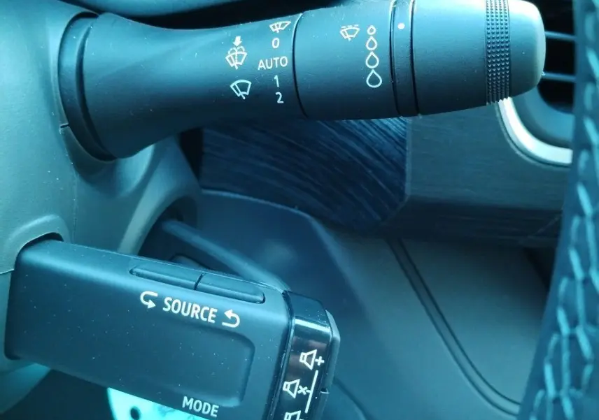 Gros plan sur les commandes de volant du Nissan Primastar 2025, avec levier d'essuie-glace et commande audio noire.