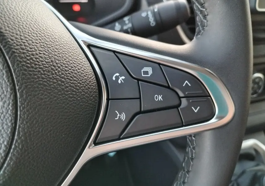 Gros plan sur les commandes multifonctions au volant en cuir noir du Nissan Primastar blanc 2025.