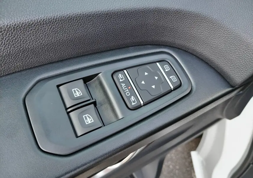 Gros plan sur les commandes de lève-vitres et rétroviseurs côté conducteur d'un Nissan Primastar blanc 2025.