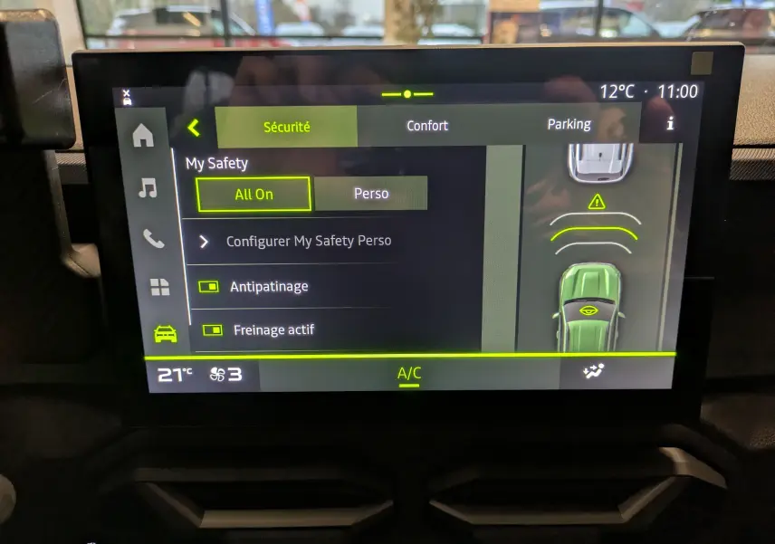 Écran tactile du tableau de bord du Dacia Duster Hybrid 140 Journey montrant les réglages de sécurité et d’aide au stationnement.