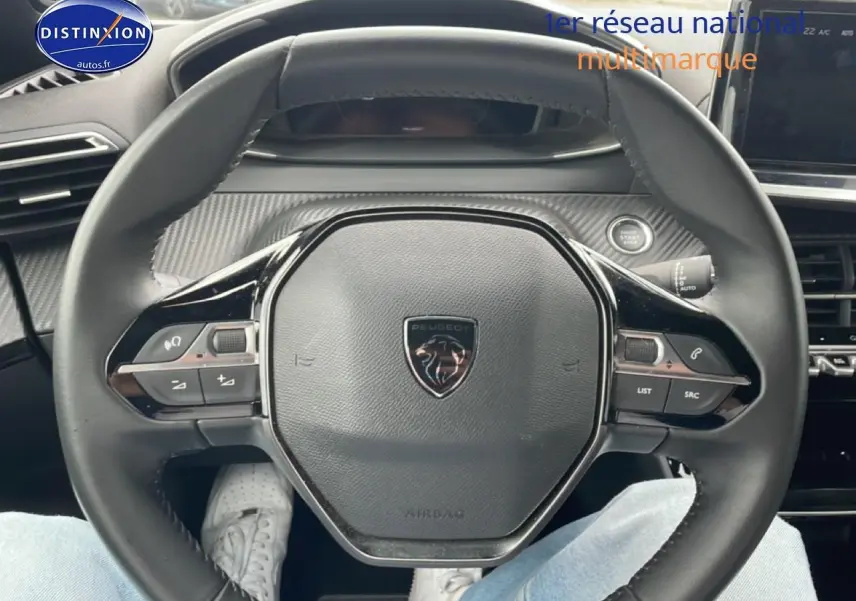 Vue rapprochée du volant multifonction noir avec logo Peugeot au centre dans l’habitacle du 2008 gris sellenium e.