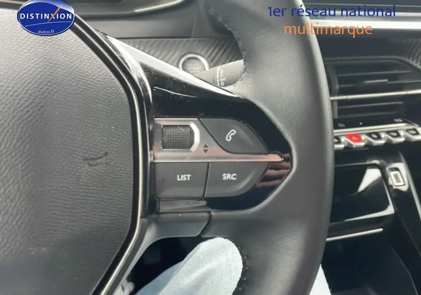 Gros plan sur le volant multifonction noir du Peugeot 2008 électrique 2025, avec commandes audio et téléphone intégrées.