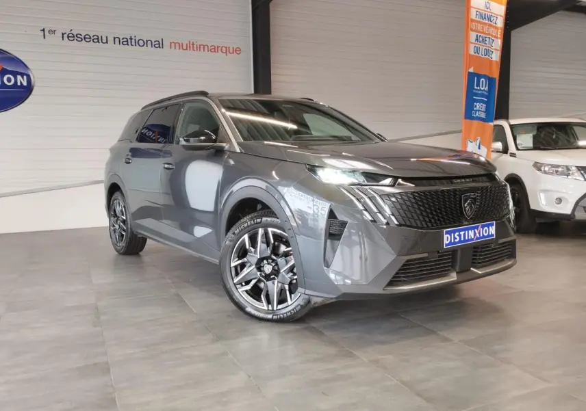 Peugeot 5008 gris titanium en 3/4 avant droit, avec calandre noire laquée et jantes alliage 19 pouces diamantées.