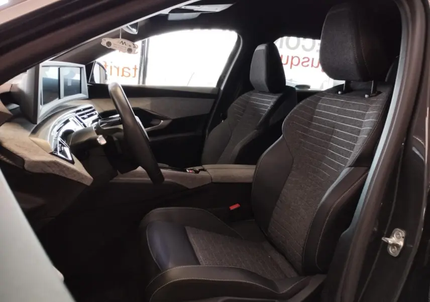Intérieur avant droit du Peugeot 5008 gris titanium 2025, sièges tissu et cuir avec tableau de bord moderne.