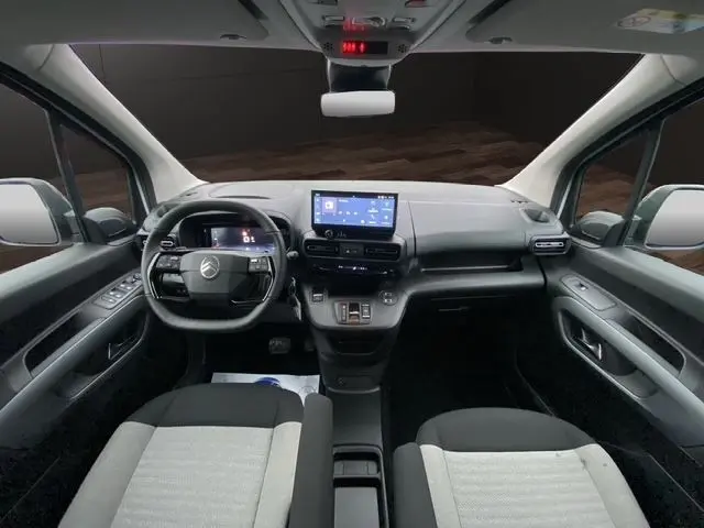 Vue intérieure avant du Citroën Berlingo blanc 2025, tableau de bord moderne avec écran tactile central et volant cuir multifonctions.