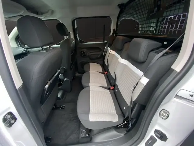 Vue intérieure côté droit du Citroën Berlingo blanc 2025, montrant la banquette arrière trois places avec séparation grillagée.