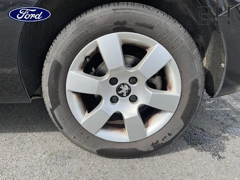 Gros plan sur la roue avant droite noire Perla Nera d’un Peugeot 5008 avec jante alu à 5 branches.