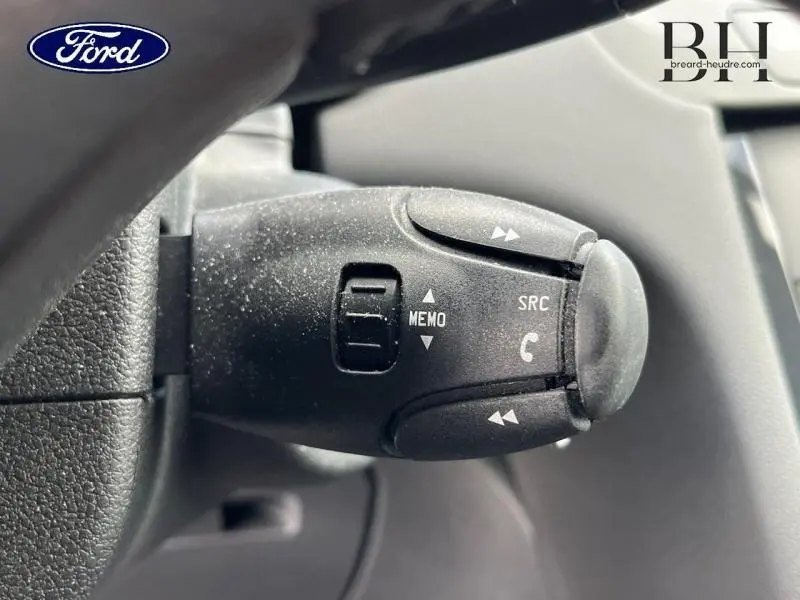 Gros plan sur la commande au volant noire avec boutons de gestion audio et téléphone, intérieur d’un véhicule Peugeot 5008 noir.