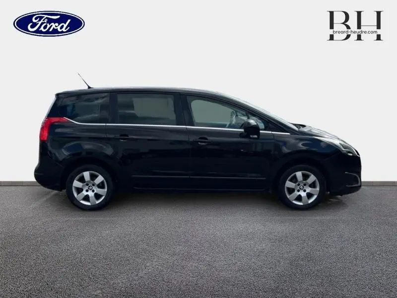 Profil droit d'un Peugeot 5008 noir Perla Nera de 2015 avec vitres arrière surteintées et jantes alu.