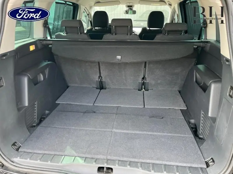 Vue arrière du coffre spacieux du Peugeot 5008 noir avec sièges arrière rabattus et tablette cache-bagages déployée.