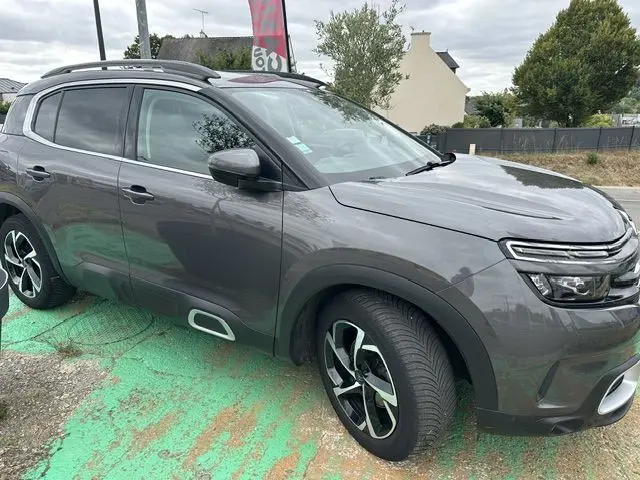 Vue 3/4 avant gauche d'un Citroën C5 Aircross marron 2020 avec jantes alliage et barres de toit noires.
