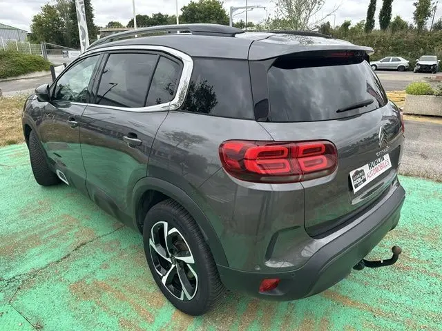 Vue 3/4 arrière droite d'un Citroën C5 Aircross marron avec feux arrière distinctifs et barres de toit visibles.