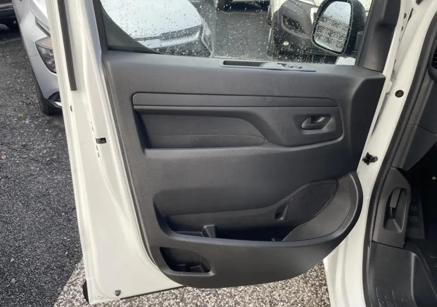 Porte avant gauche ouverte d'un Opel Vivaro blanc 2024, panneau intérieur noir avec haut-parleur intégré.