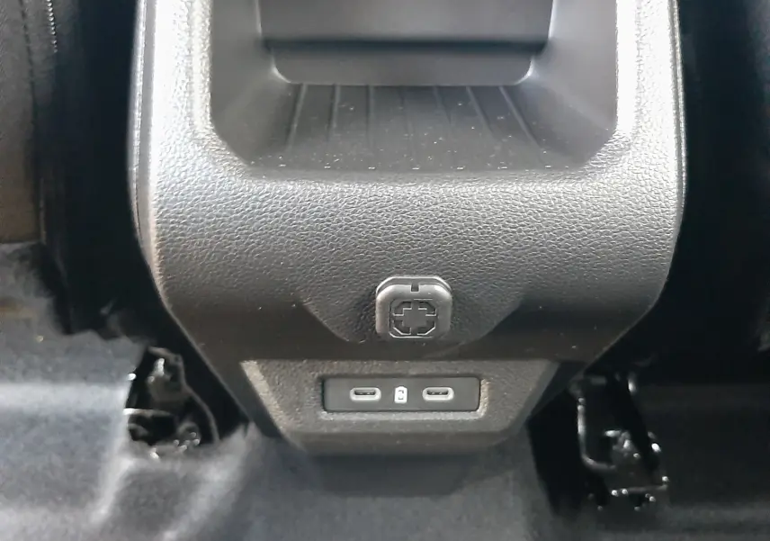 Prise USB arrière double et rangement en plastique noir dans l'habitacle du Dacia Duster 2025 couleur Sandstone.