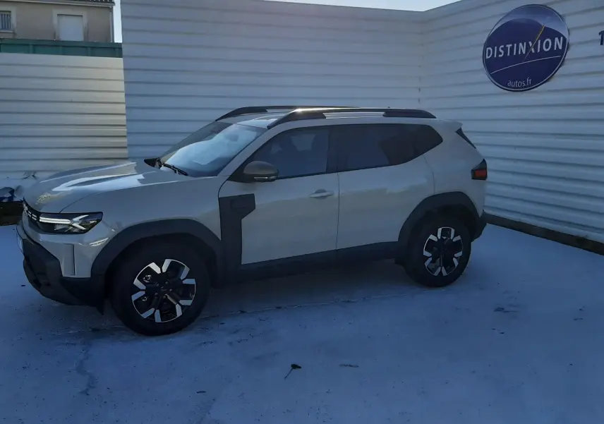 Dacia Duster 1.6 Hybrid 140ch Extreme en couleur Sandstone, vue 3/4 avant côté gauche avec jantes bi-ton et barres de toit.