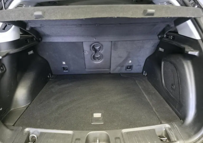 Coffre ouvert vu de l'arrière du Jeep Compass gris foncé, montrant l'espace de chargement et les finitions intérieures noires.