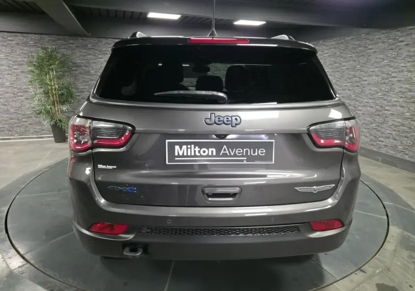 Vue arrière d'un Jeep Compass gris foncé avec hayon électrique et badges Trailhawk et 4xe visibles.